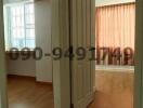 Interior view of a room entrance with wooden flooring and curtain