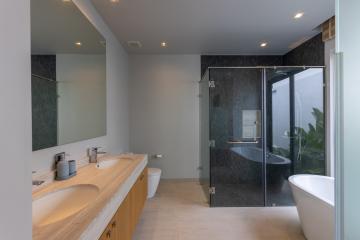 Modern spacious bathroom with dual vanities, glass shower, and freestanding tub