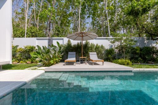 Stylish backyard with pool, sun loungers, and lush garden