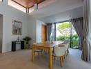Spacious and bright modern dining room with wooden table, high ceiling, and garden view