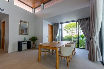 Spacious and bright modern dining room with wooden table, high ceiling, and garden view