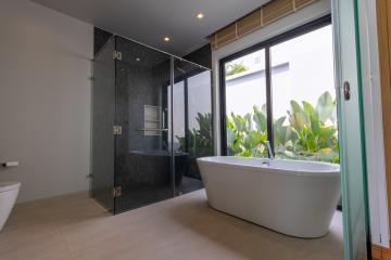 Modern bathroom with a freestanding tub, walk-in shower, and green plants