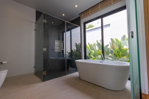 Modern bathroom with a freestanding tub, walk-in shower, and green plants