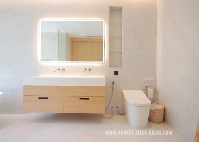 Modern bathroom with bright lighting, floating vanity, and mirrored cabinet