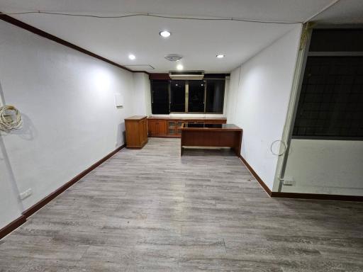 Spacious empty room with wooden flooring and built-in cabinets