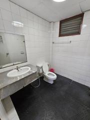 Compact bathroom with tile walls, a sink, toilet, and dark flooring