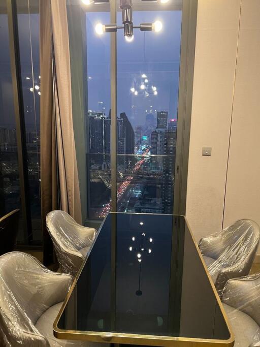 Modern dining area with large window overlooking cityscape at night