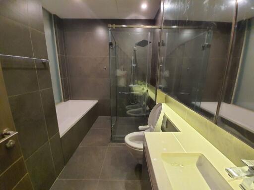 Modern bathroom with glass shower cubicle, tiled walls, and integrated lighting
