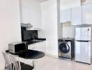 Modern kitchen with white cabinets, stainless steel appliances, and a small dining area