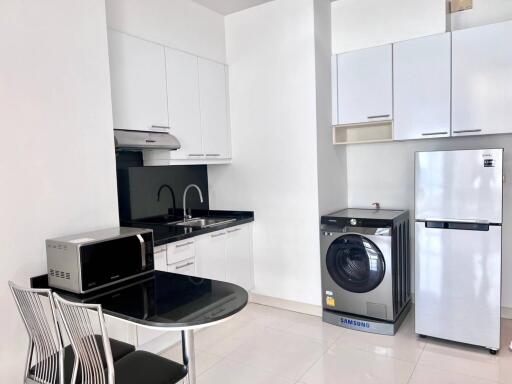 Modern kitchen with white cabinets, stainless steel appliances, and a small dining area