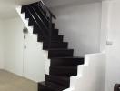 Modern staircase with dark wood steps and white walls in a residential home