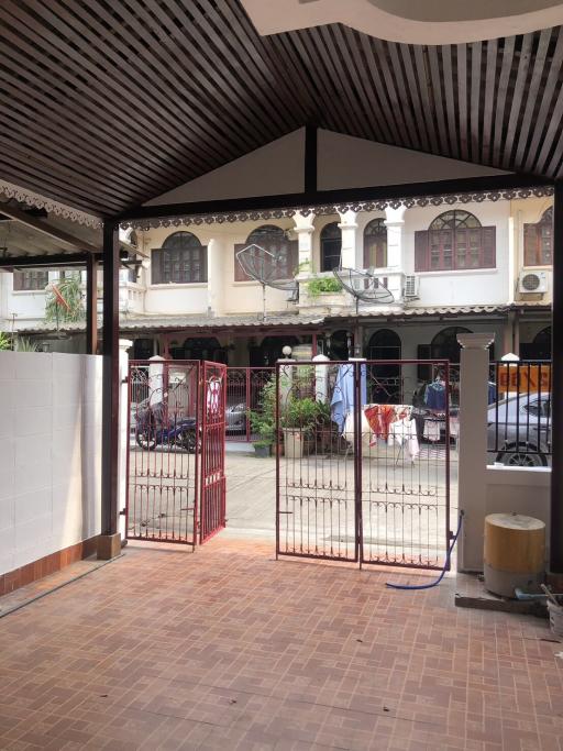 View of a residential building entrance with gate and tiled outdoor space