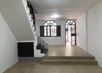 Open floor plan living area with staircase and arched windows