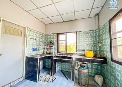 Bright and spacious kitchen in need of modernization with a large window and tiled walls
