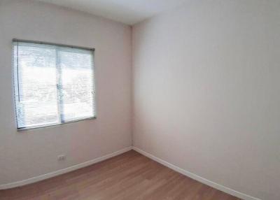 Spacious empty bedroom with a large window and hardwood floors