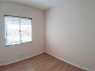 Spacious empty bedroom with a large window and hardwood floors