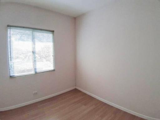 Spacious empty bedroom with a large window and hardwood floors