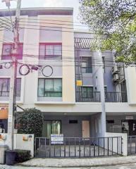 Modern three-story residential building with a gray facade and balcony features