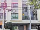 Modern three-story residential building with a gray facade and balcony features