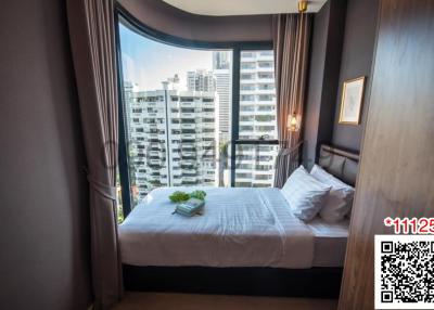 Modern bedroom with a comfortable bed, large windows, and city view