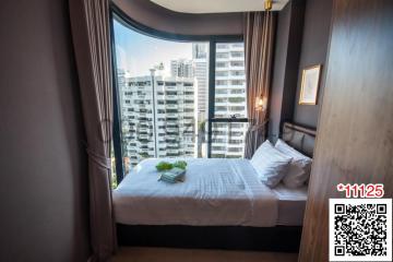 Modern bedroom with a comfortable bed, large windows, and city view