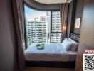 Modern bedroom with a comfortable bed, large windows, and city view