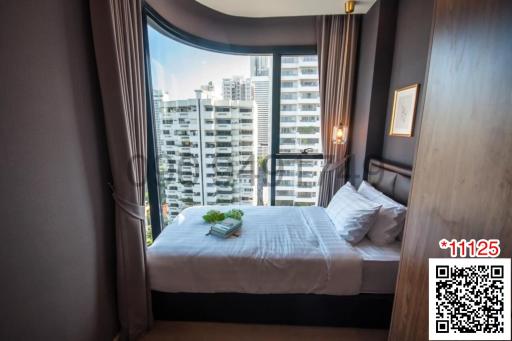 Modern bedroom with a comfortable bed, large windows, and city view