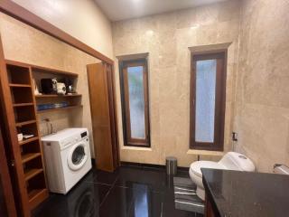 Modern bathroom with shelving, washing machine, and frosted glass windows