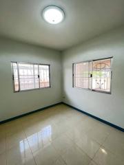 Bright empty bedroom with tiled floor and two large windows