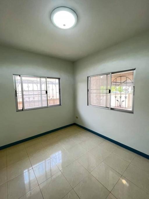 Bright empty bedroom with tiled floor and two large windows