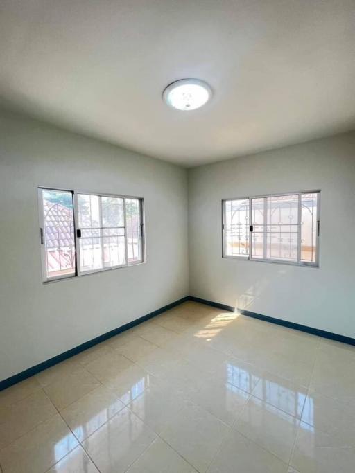 Spacious and well-lit bedroom with tiled flooring and large windows