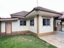 Suburban single-story house with light colored exterior, tiled roof, and fenced windows