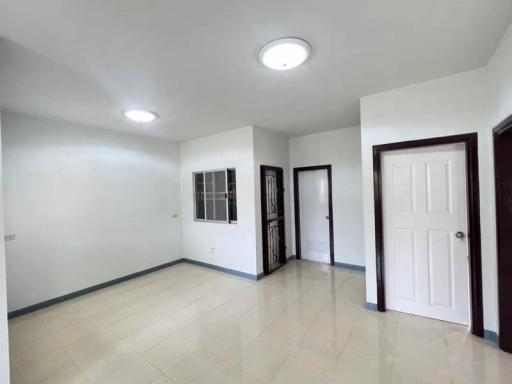 Spacious empty room with tiled flooring, bright ceiling lights, and multiple doors