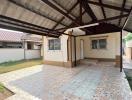 Covered outdoor patio area with tiled flooring adjacent to a residential property