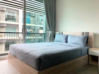Modern bedroom with large bed and a view of adjacent buildings