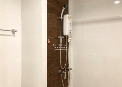 Compact bathroom with modern electric shower and sleek white tiles