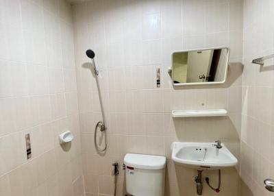 Compact tiled bathroom with toilet, sink, and shower