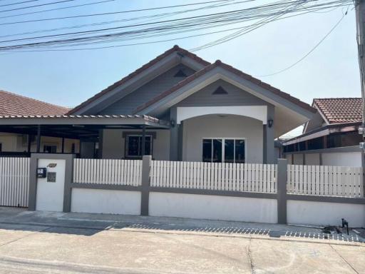 Single-story residential home with white fence and clear blue sky