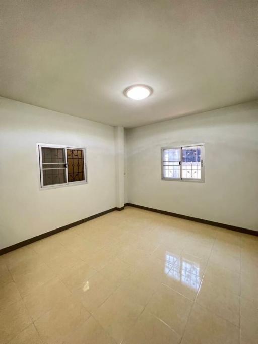 Spacious empty bedroom with tiled flooring and natural light from windows