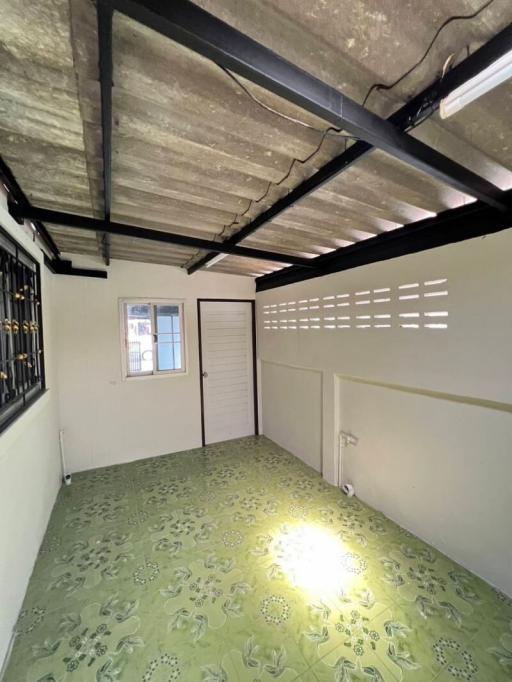 Well-lit basement room with exposed beams and floral carpet