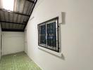 Indoor view of a building featuring green tiled flooring and a window with security bars