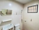 Compact bathroom with tiled walls, basic sanitary fittings, and natural light