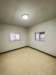 Empty bedroom with two windows and tiled flooring