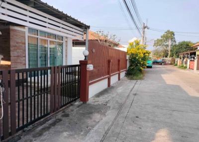 Street view of a single-story residential home with fenced yard and paved driveway