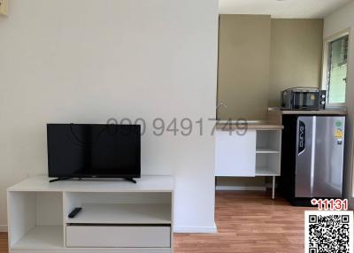 Compact living room with a TV, refrigerator, and a small dining area