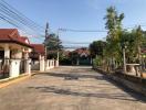 Spacious residential street view with single-story homes and clear sky