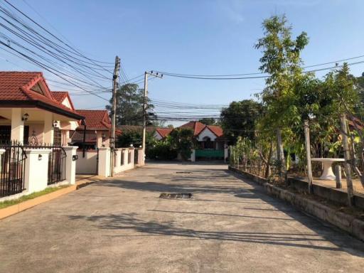 Spacious residential street view with single-story homes and clear sky