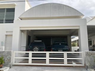 Modern two-story house facade with a double garage and two vehicles parked