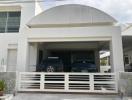 Modern two-story house facade with a double garage and two vehicles parked