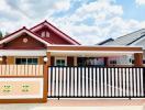 Front view of a single-story residential home with red roof and secure fence